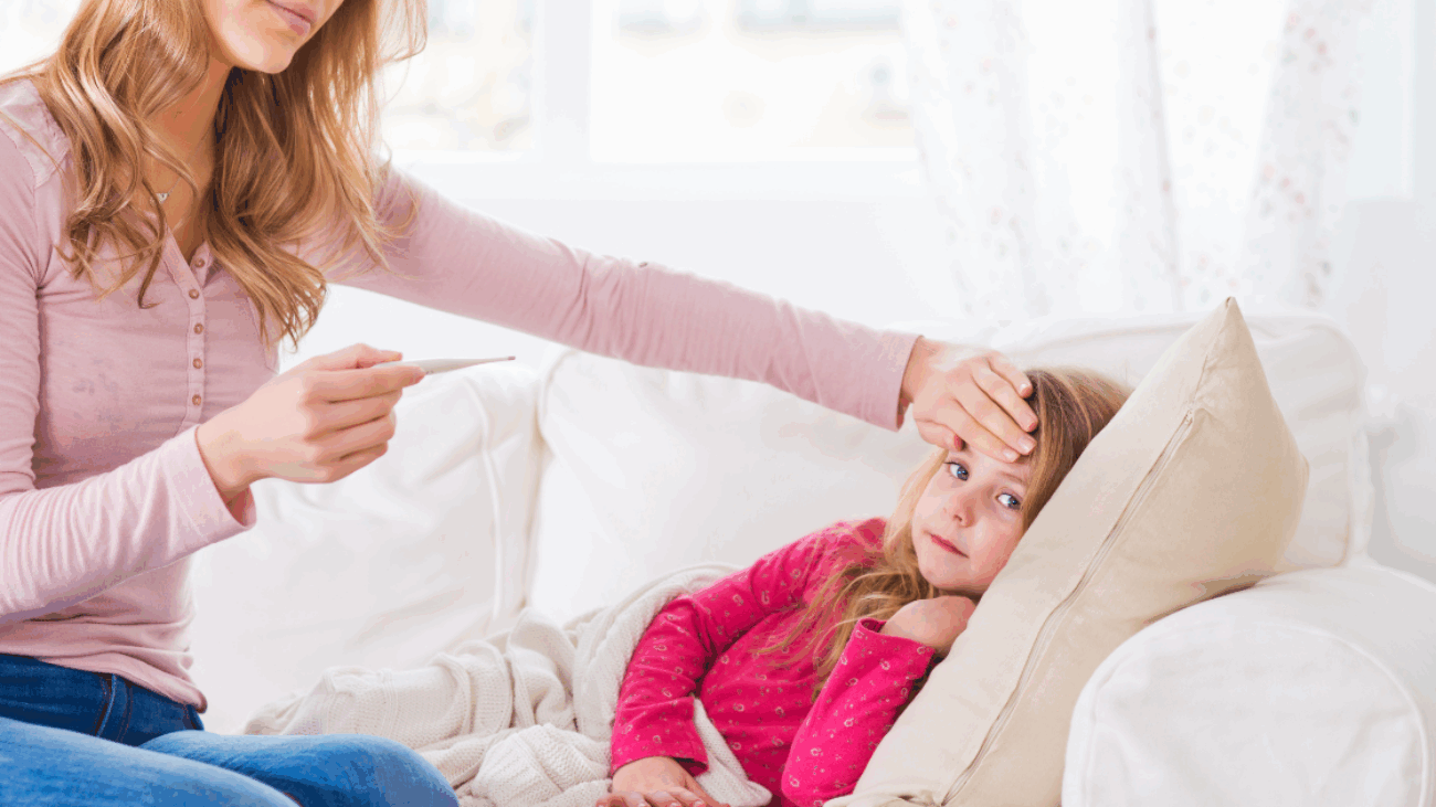 Mother checking daughter's temperature at home, unaware of asymptomatic contagion risks.