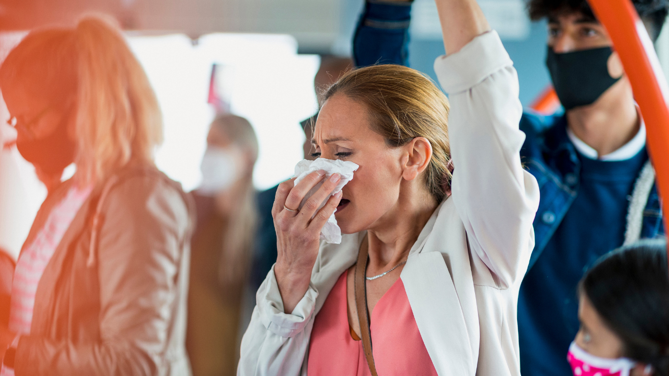 Woman sneezing on a crowded bus, showing how airborne diseases spread in enclosed spaces.